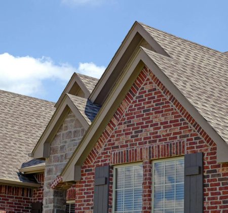 A charming brick house featuring a sloped roof and decorative shutters on its windows