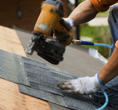 A man skillfully operates a nail gun to secure a roofing shingle in place on a construction project.